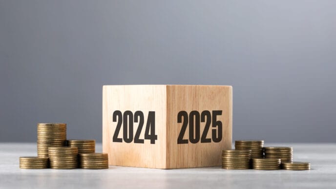 Wooden blocks transitioning from 2024 to 2025, accompanied by neatly stacked coins, symbolizing financial growth and preparation for the upcoming year | Meridian Source