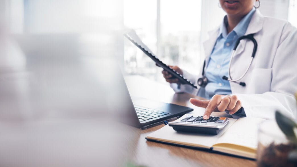 Accounting doctor, calculator and hands of person calculating bookkeeping finance, hospital budget or medical savings. Mockup space, healthcare and accountant working on taxes, audit or compliance | Meridian Source