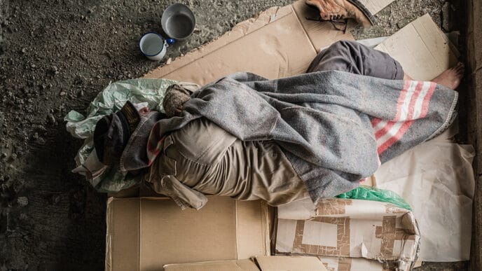 Old,Homeless,Man,Wearing,Sweater,And,Blanket,Sleeping,On,Cardboard | Meridian Source