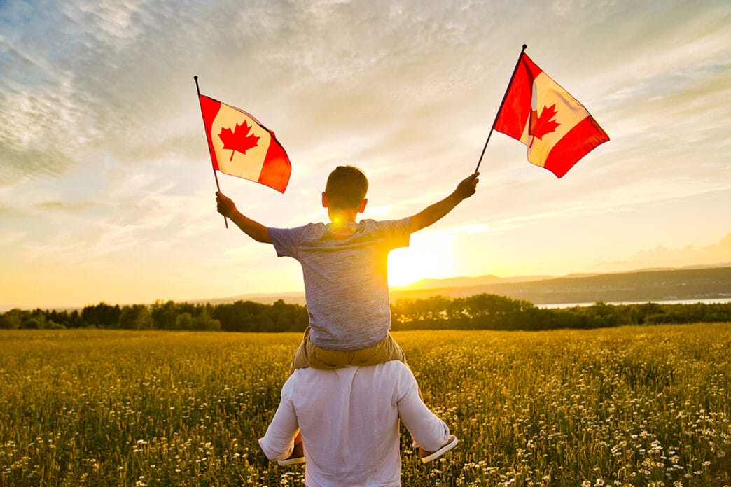 Adorable cute happy Caucasian boy holding Canadian flag on the father shoulder | Meridian Source