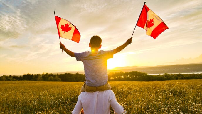 Adorable cute happy Caucasian boy holding Canadian flag on the father shoulder | Meridian Source