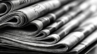 Close-up image of several neatly folded newspapers in black and | Meridian Source