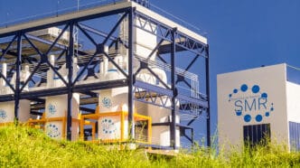 concept of a SMR small modular nuclear reactor power plant on a sunny day SMR is a future energy concept 3d rendering | Meridian Source