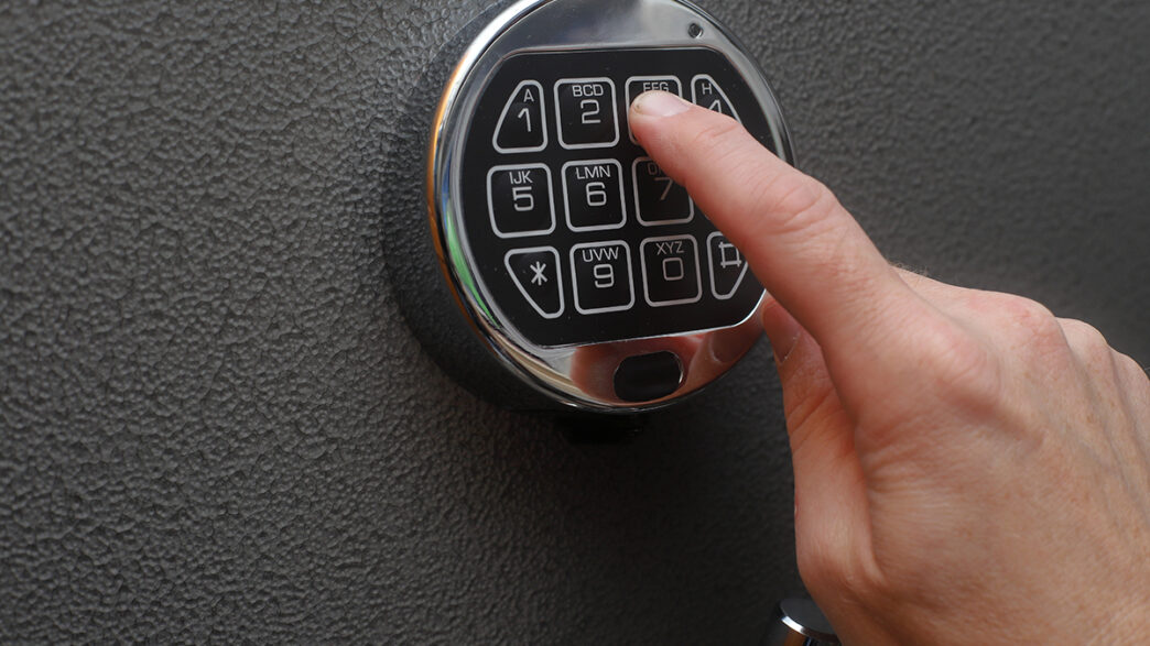 Hand enters combination on digital lock on a safe | Meridian Source