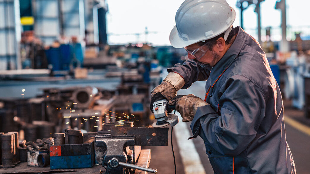 Skilled industrial worker grinding metal part | Meridian Source