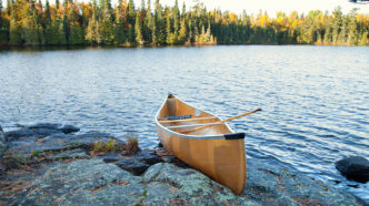Yellow canoe on rocky shore of northern Minnesota lake at sunris | Meridian Source