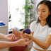 A woman patient examines rehabilitation equipment with a therapist in a clinics treatment room | Meridian Source